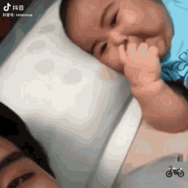 a baby laying on a pillow with a motorcycle in the foreground