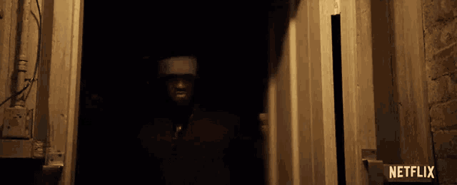 a man with a bandage on his head is standing in a doorway in a dark room .