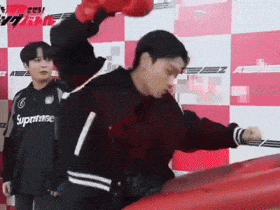 a man wearing red boxing gloves is standing in front of a red boxing ring .