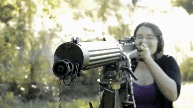 a woman in a purple tank top is holding a gun in her hand