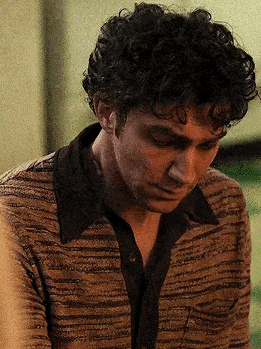 a close up of a man with curly hair wearing a striped shirt .
