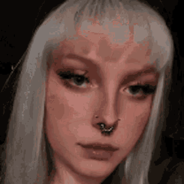 a close up of a woman 's face with a nose ring and white hair .