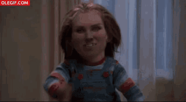 a close up of a doll with its arms outstretched and a woman behind it .