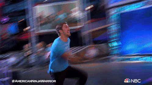 a man in a blue shirt is running in front of a nbc sign