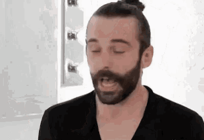 a man with a beard and a bun is wearing a black shirt .