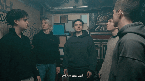 a group of young men are standing in a dark room and one of them says where are we