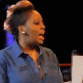 a woman in a blue shirt is making a funny face and sticking out her tongue .