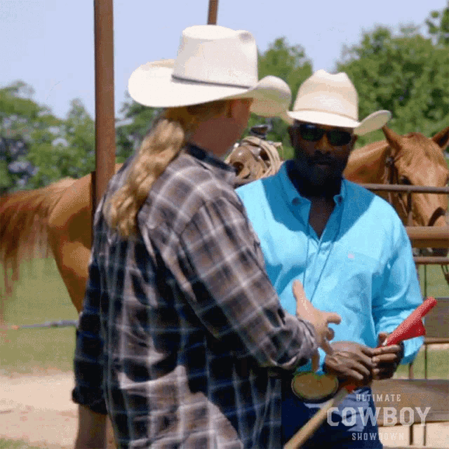two men wearing cowboy hats and plaid shirts are talking to each other in front of a horse ..