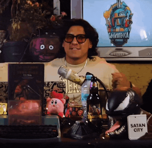 a man sitting in front of a television with a sign that says satan city