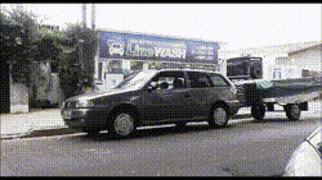 a car with a trailer is parked in front of a car wash