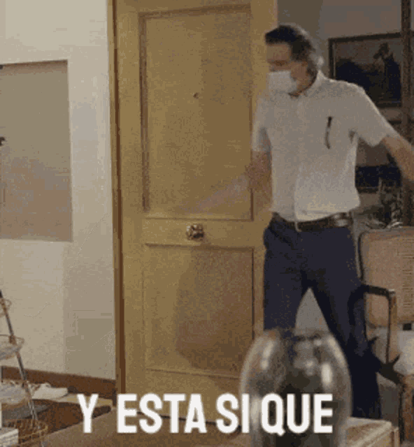 a man wearing a mask is standing in front of a door with the words y esta si que written below him