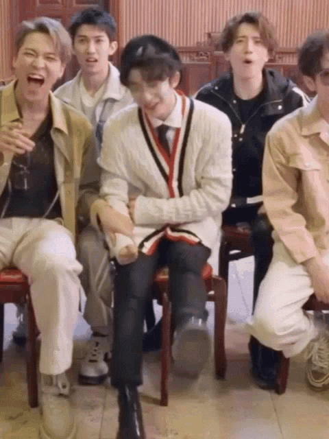 a group of young men are sitting in chairs laughing