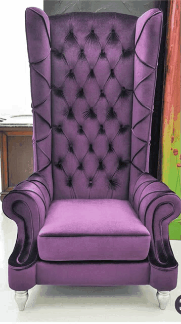 a purple tufted chair with silver legs sits in front of a painting