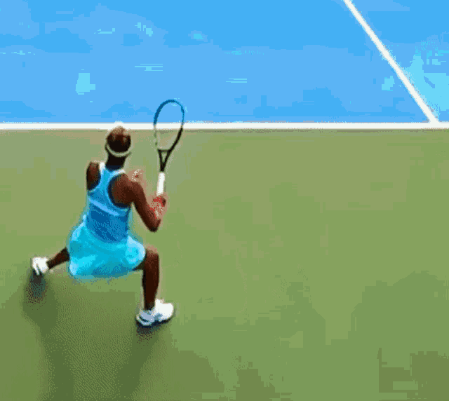 a woman is playing tennis on a blue court while holding a tennis racquet .
