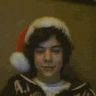 a young man wearing a santa hat and headphones is holding a cell phone .