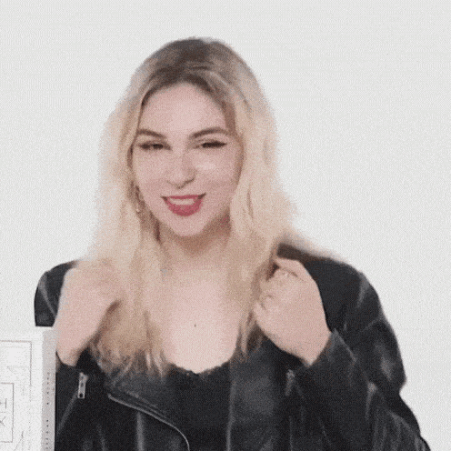 a woman wearing a black leather jacket and a black top is making a funny face .
