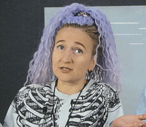 a woman with purple hair is wearing a skeleton sweater .