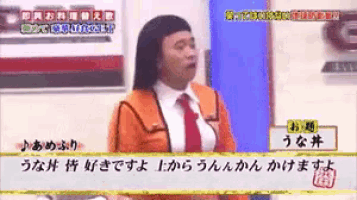 a man in an orange suit and red tie is talking in a foreign language