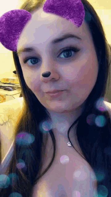 a woman wearing a snapchat filter with purple ears on her face