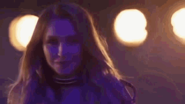 a close up of a woman 's face in a dark room with purple lights .