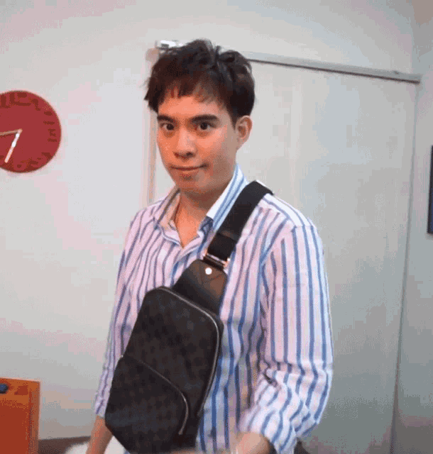 a man wearing a striped shirt is carrying a black purse