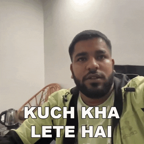 a man with a beard wearing a yellow jacket says kuch kha lete hai