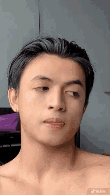 a young man without a shirt is looking at the camera .