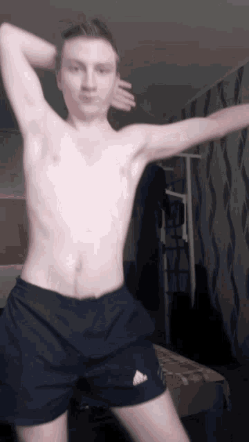 a shirtless man wearing black adidas shorts is dancing