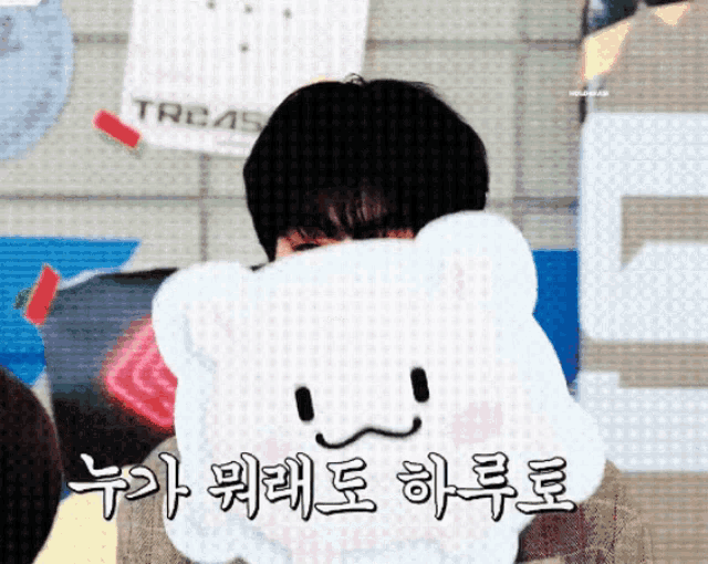 a person covering their face with a stuffed animal with a face on it in front of a sign that says treas