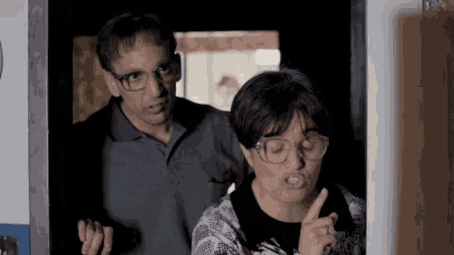 a man wearing glasses is standing next to a woman