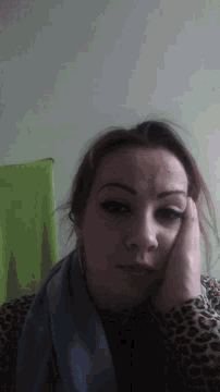 a woman in a leopard print shirt is laying down with her hand on her face