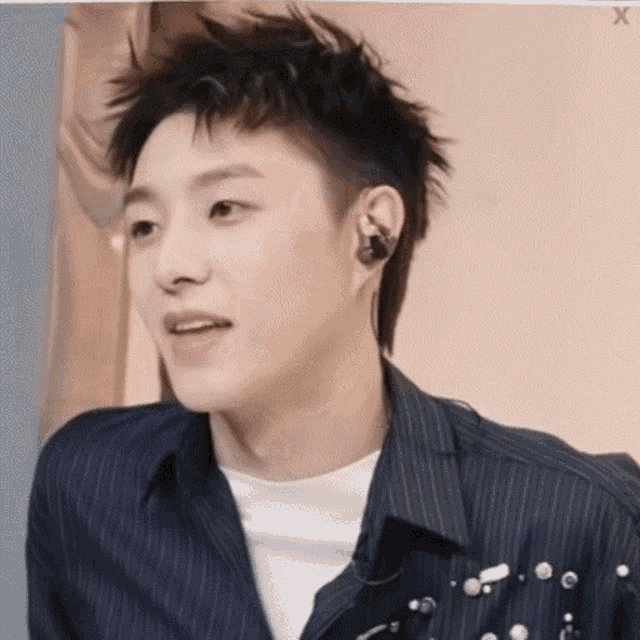 a young man wearing a striped shirt and earphones is looking at the camera .