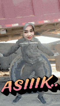 a woman in a hijab is standing next to a tire with the word asmuk written on it