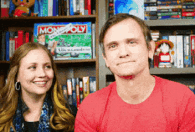 a man and a woman are standing in front of a monopoly game