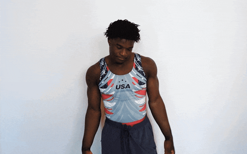 a man wearing a usa tank top stands in front of a white wall