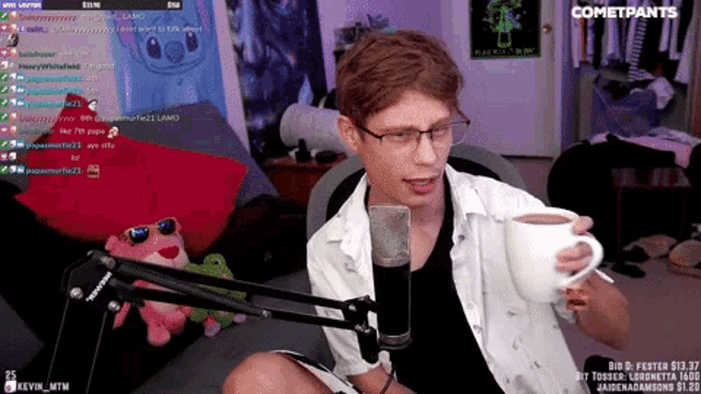 a man holding a cup in front of a microphone with cometpants written on the bottom right