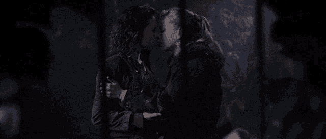a man and woman are kissing in a dark room