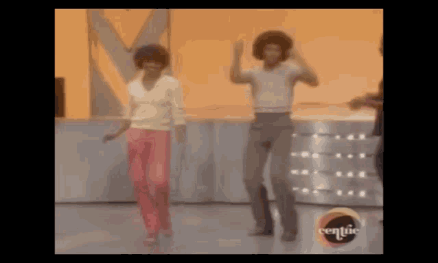 a man and a woman are dancing on a stage . the woman is wearing pink pants .