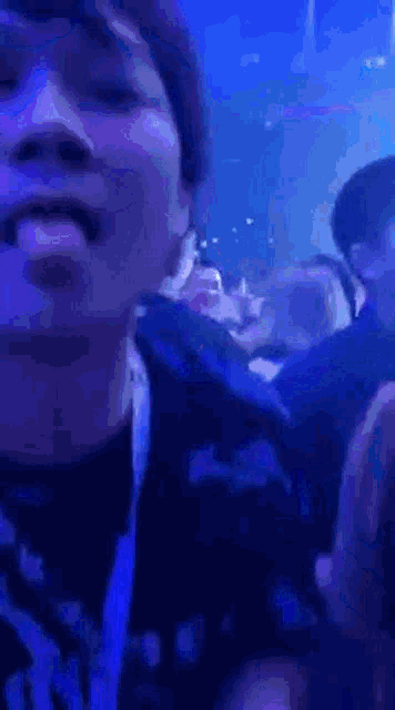 a man is sticking his tongue out while sitting in a crowd at a concert .
