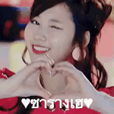 a woman is making a heart shape with her hands and smiling