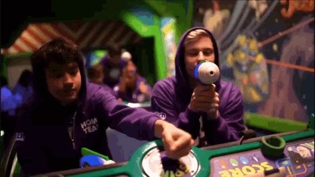 two men in purple hoodies are playing a game with the word score on the screen