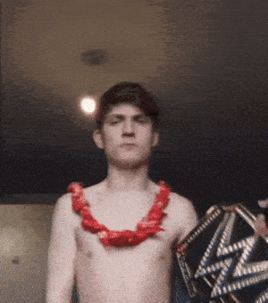 a shirtless man with a red lei around his neck is holding a trophy