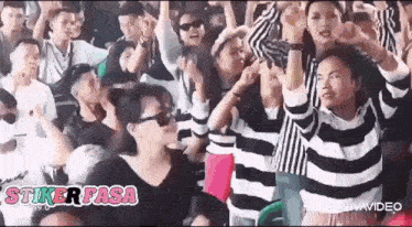 a crowd of people wearing striped sweaters are dancing at a party .