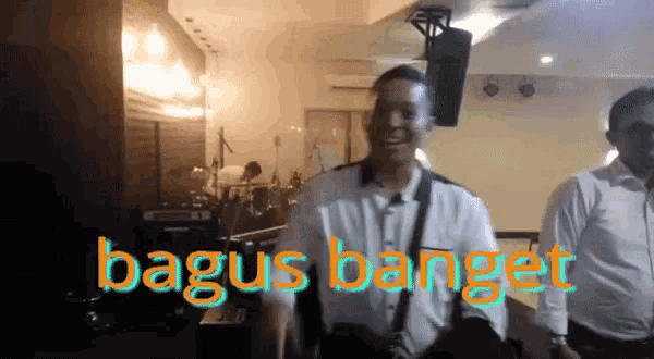 two men are standing in front of a sign that says bagus banget on it