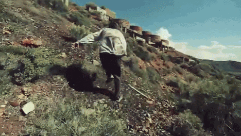 a man is running down a hill with a train in the background
