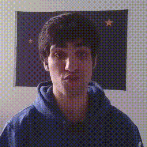 a man in a blue hoodie stands in front of a flag