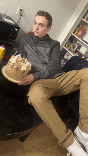 a man sitting on a table holding a cake with candles