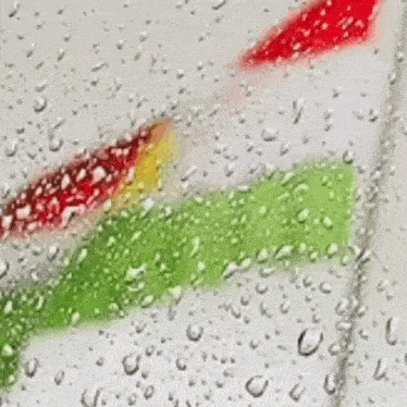 a close up of water drops on a glass with a red yellow and green stripe