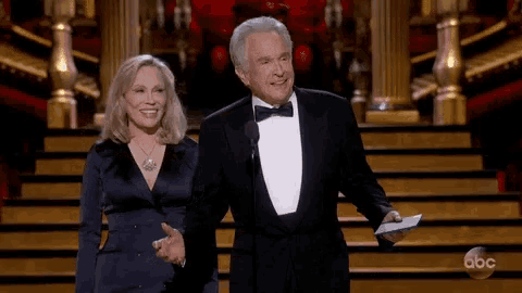 a man in a tuxedo and a woman in a blue dress are on a stage with abc written on the bottom
