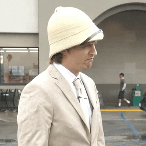 a man wearing a tan suit and a white hat
